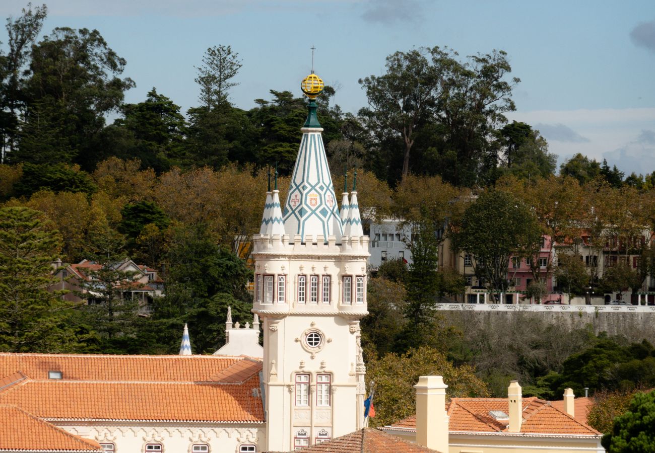 View of Sintra Town Hall with its iconic tower, surrounded by historic buildings and lush green hills.