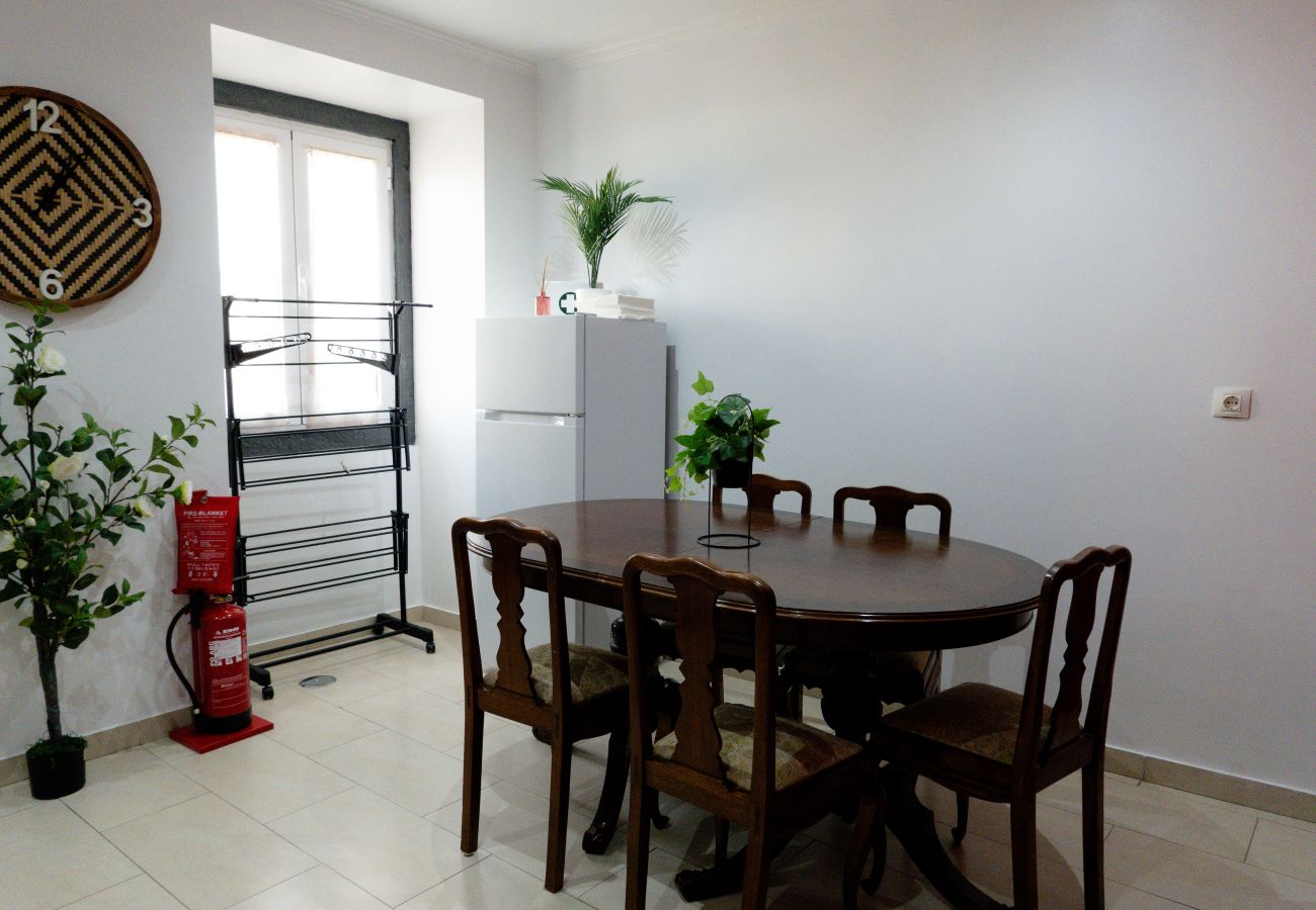 Dining room with round wooden table, four chairs, and plant decorations.