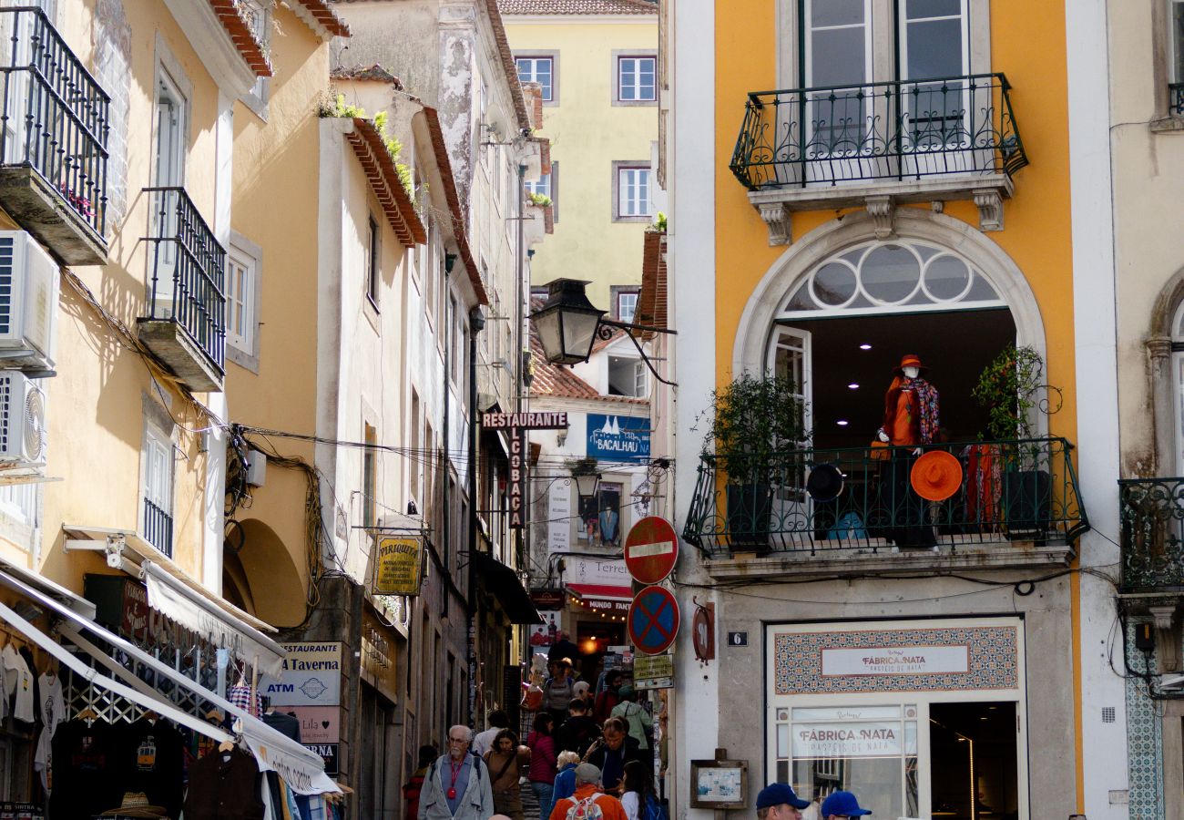 Aerial view of a busy street in Sintra, featuring outdoor cafés, umbrellas, and tourists exploring shops and restaurants.