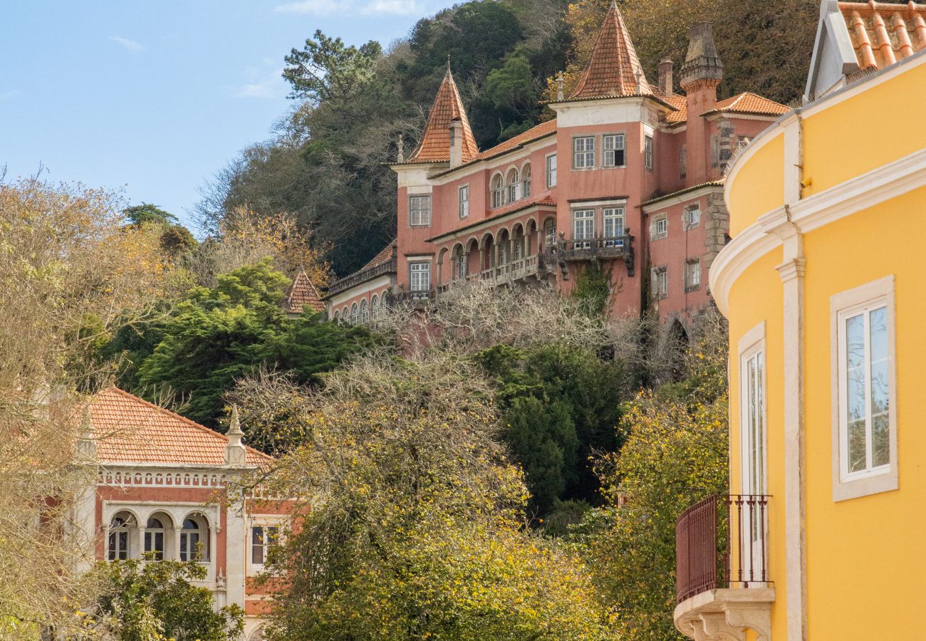 View of Sintra with its colorful houses, surrounded by green hills and lush trees.