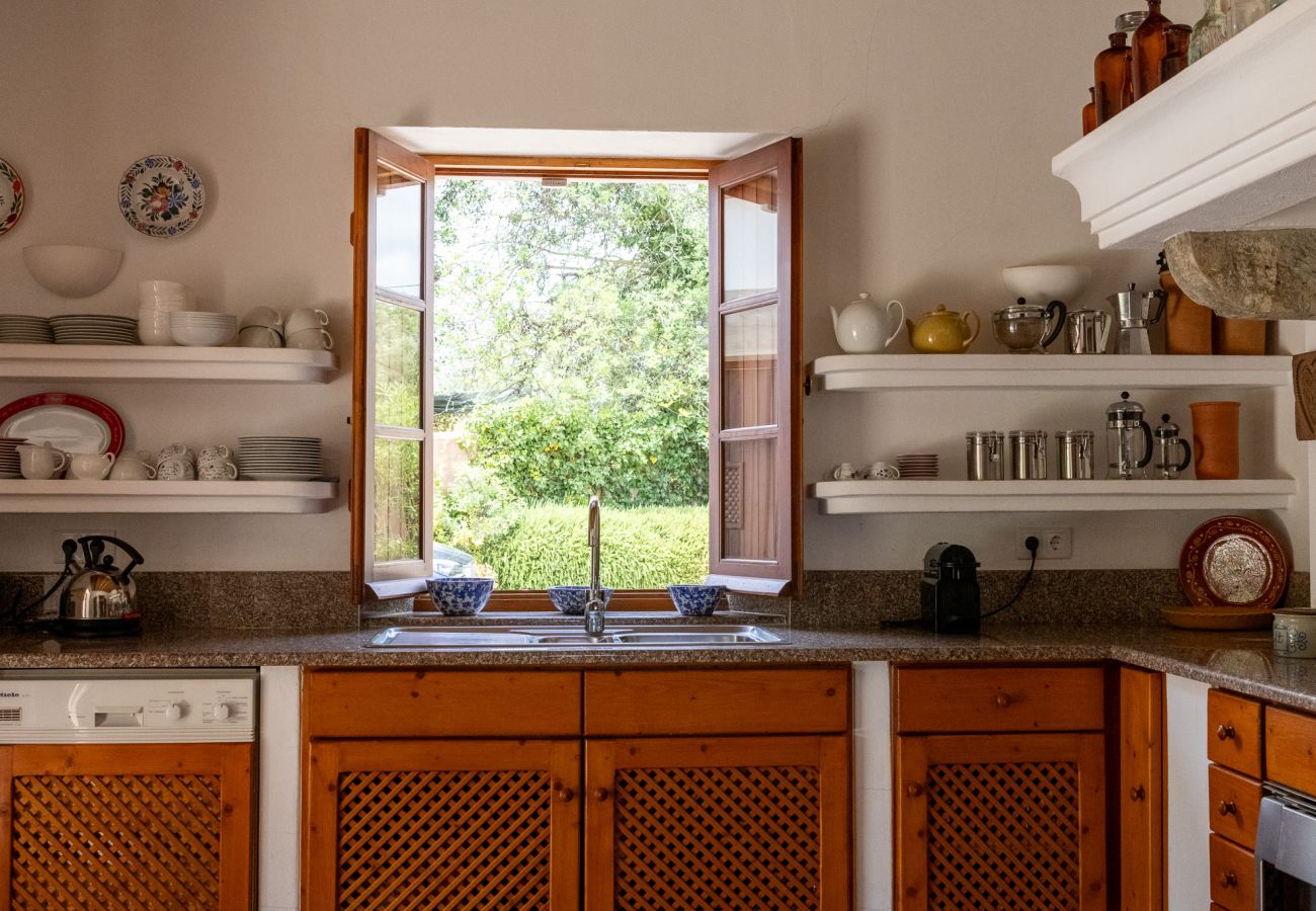 Rustic-style kitchen in Almancil, featuring wooden cabinets, open shelves, and a window overlooking the garden.