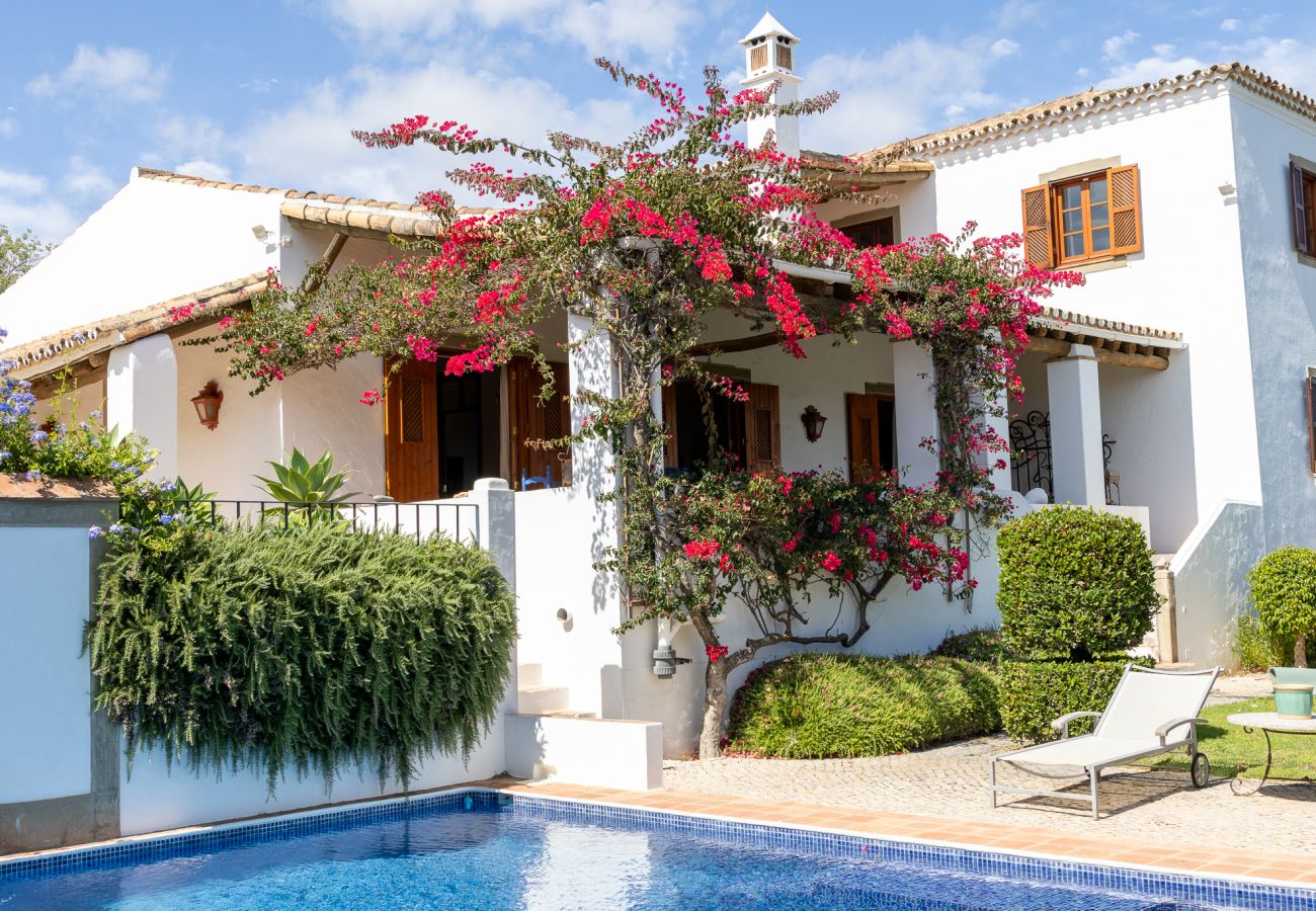 Countryside house in Almancil with a swimming pool, vibrant flowers, and traditional Algarve architecture.