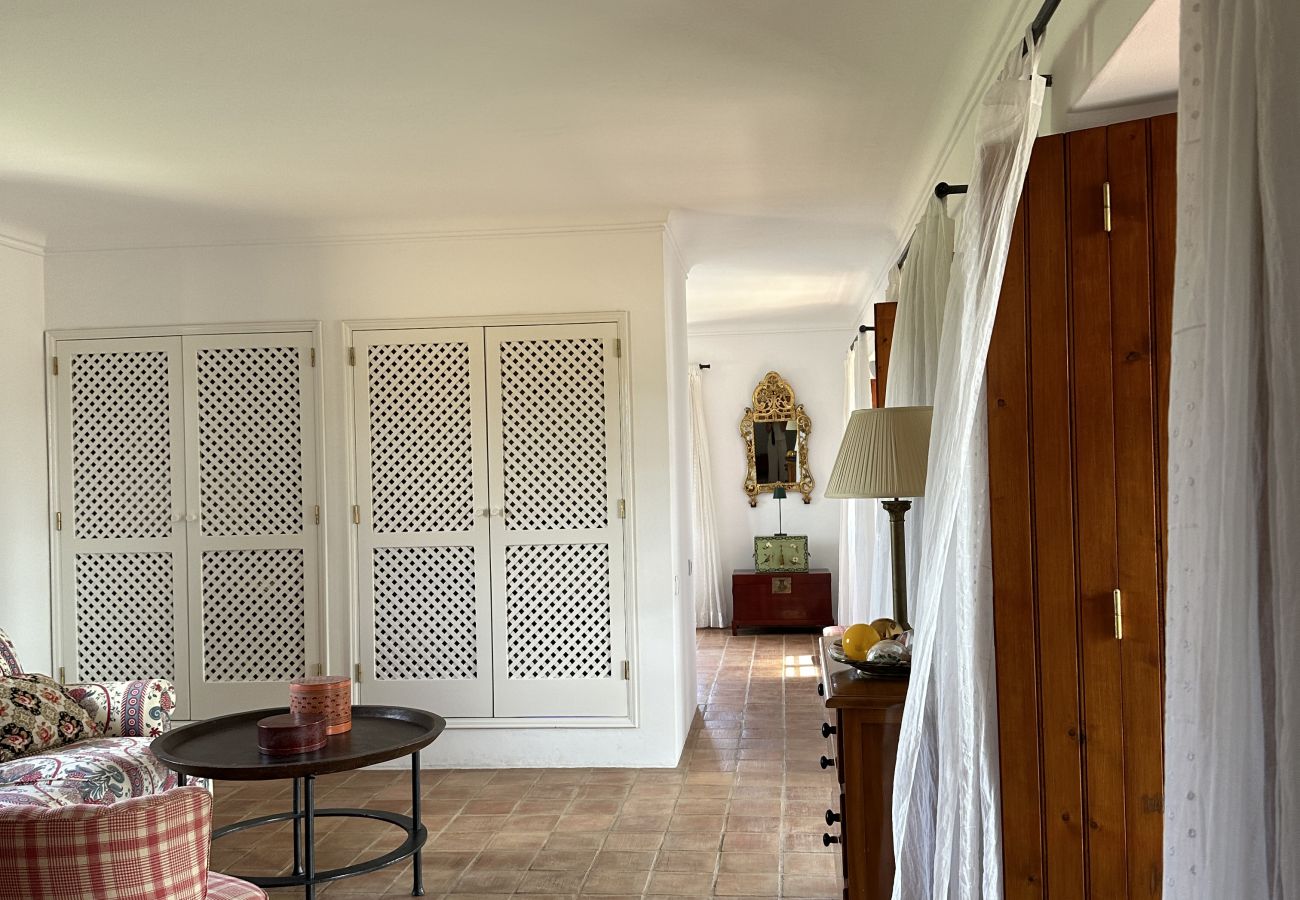 Bright corridor with terracotta flooring, wooden doors, and rustic decorative details.