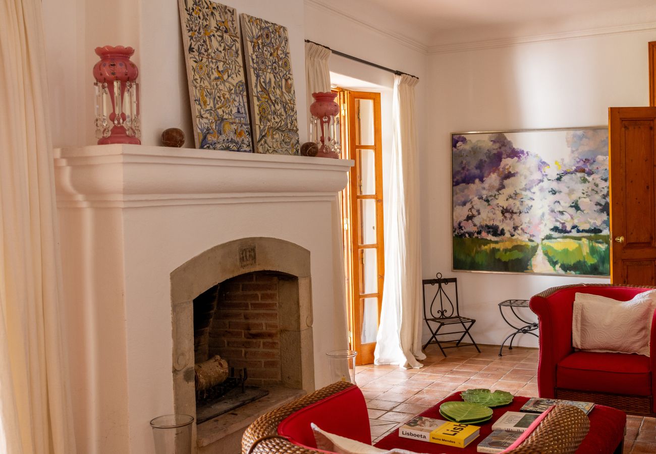 Spacious living room with a fireplace, red sofas, and rustic decor in Almancil.