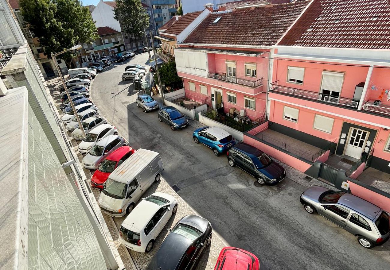View from the balcony overlooking a busy street with parked cars and colorful buildings, including a pink traditional-style building.