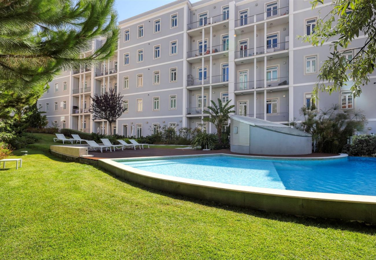 Sparkling blue pool surrounded by lush gardens and sun loungers, with the elegant Residência Sotto Mayor building in the background.