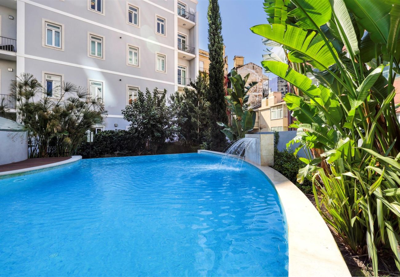  Stylish outdoor pool surrounded by lush greenery, featuring a waterfall for a relaxing atmosphere.