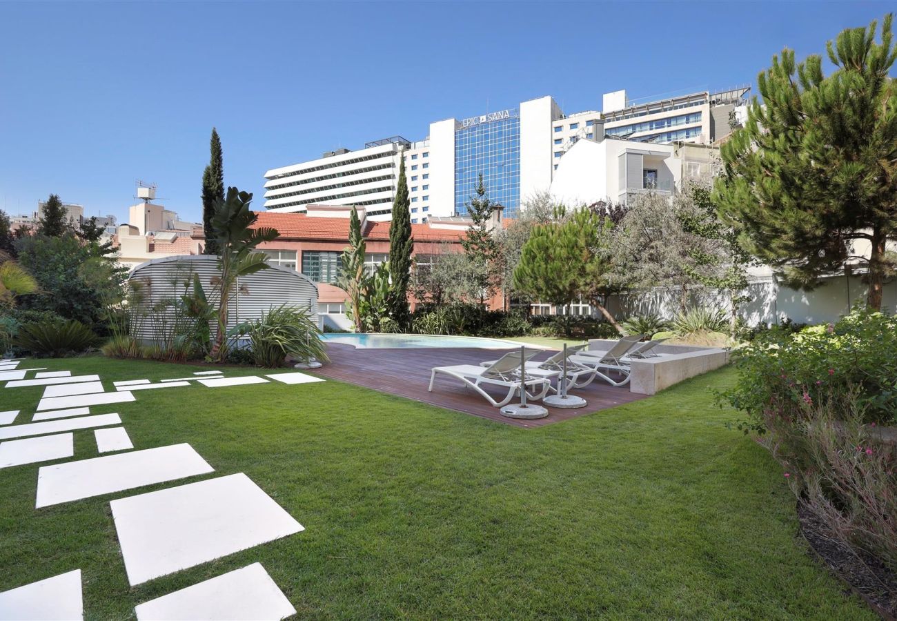 Spacious private garden featuring a wooden deck, sun loungers, and lush greenery, perfect for outdoor relaxation.