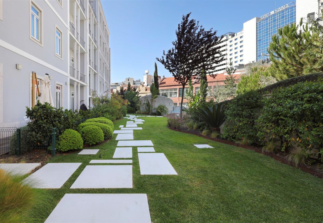 Well-maintained private garden featuring a stone pathway surrounded by lush greenery and open green spaces.