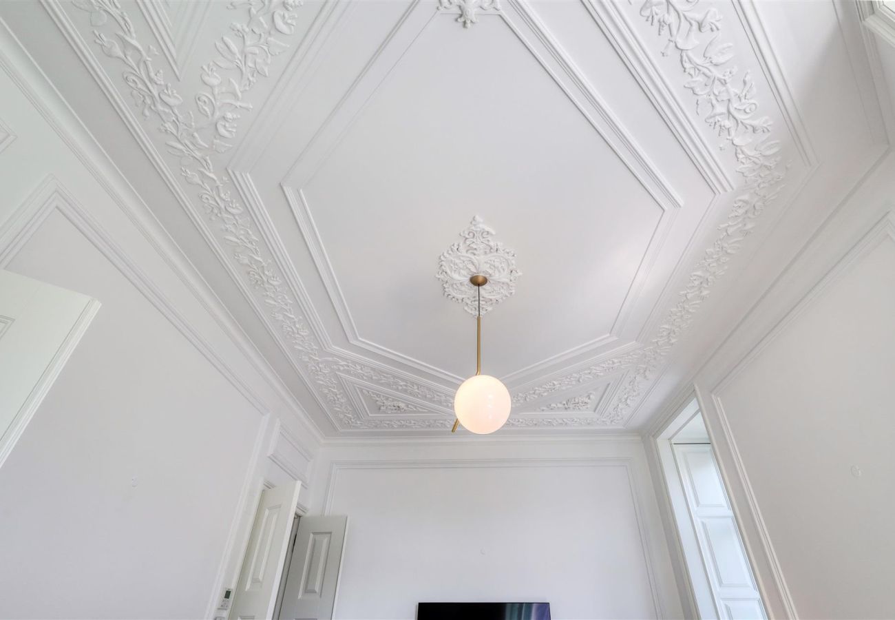 White ceiling with classic ornate moldings and a pendant light in an elegant and sophisticated setting.