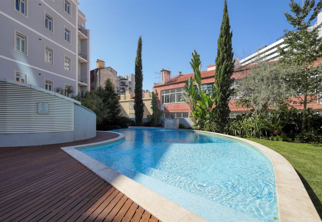 Stylish outdoor pool surrounded by a wooden deck and lush greenery, offering a relaxing atmosphere.