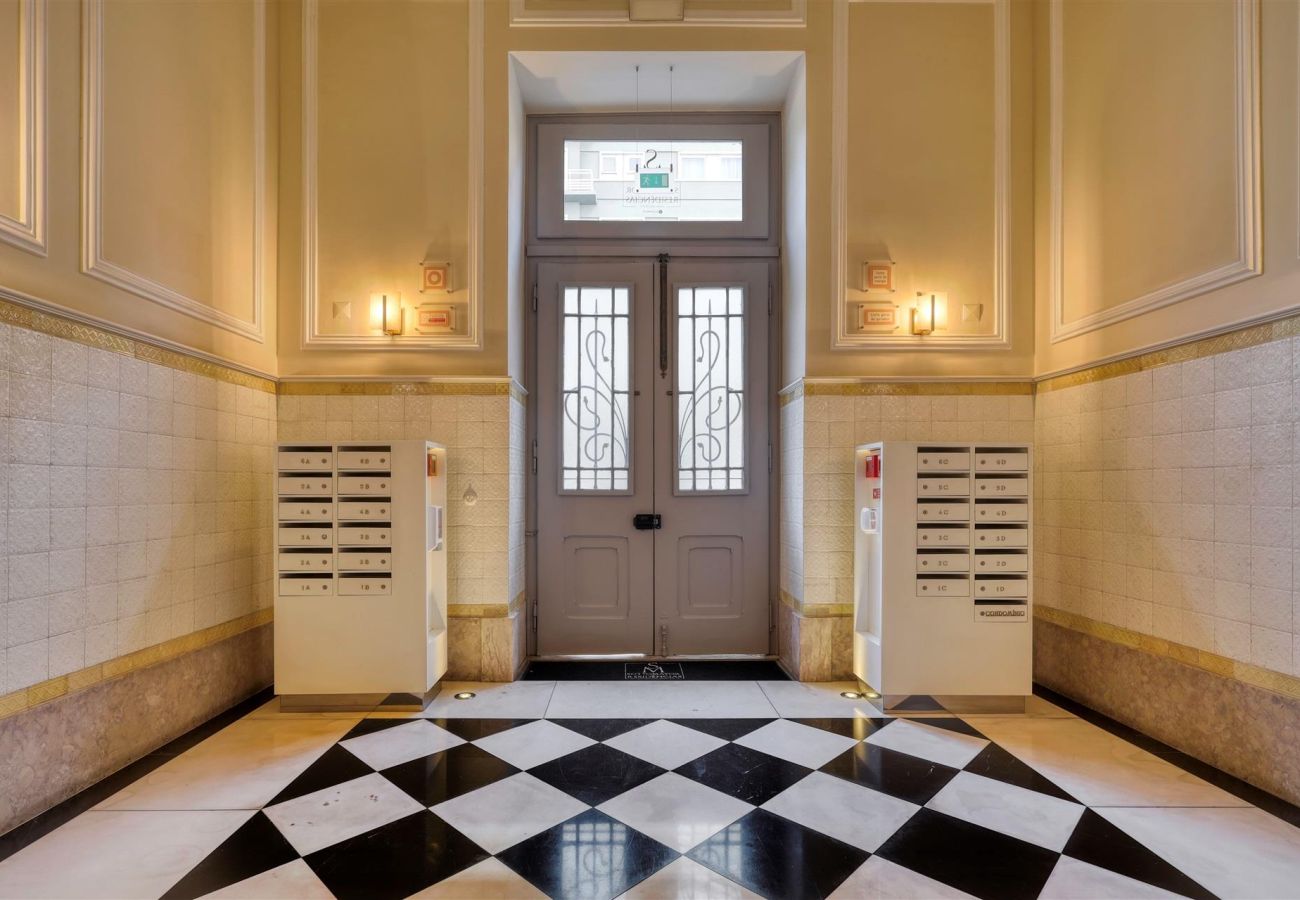 Building entrance hall with black and white marble flooring, warm lighting, and classic mailboxes.