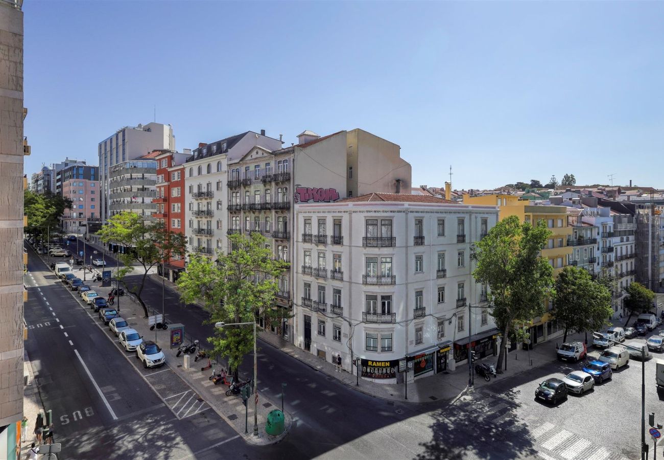 Panoramic view of a bustling Lisbon street, featuring classic and modern buildings under a clear blue sky.