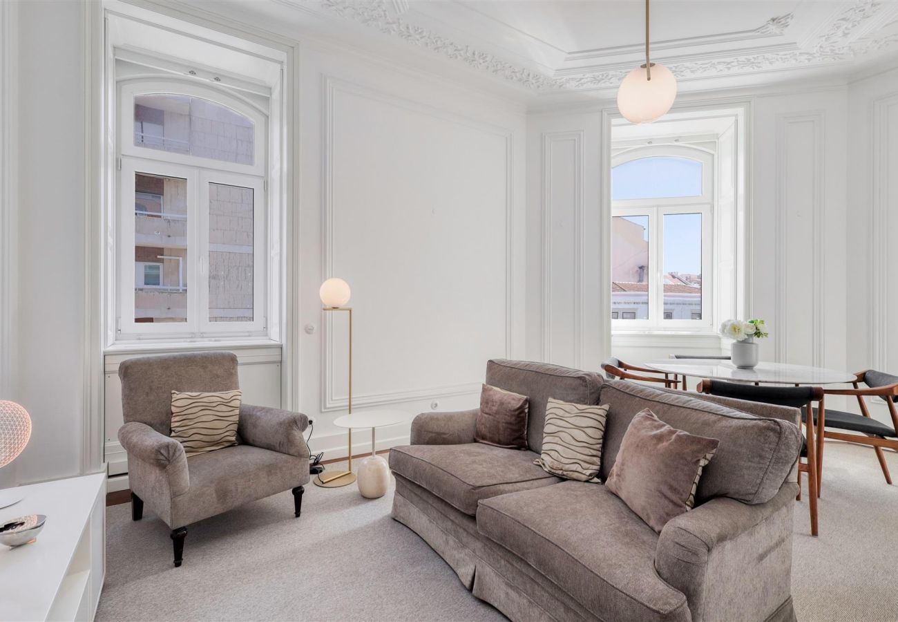 Sophisticated living room with comfortable furniture, large windows, and ornate ceiling details.
