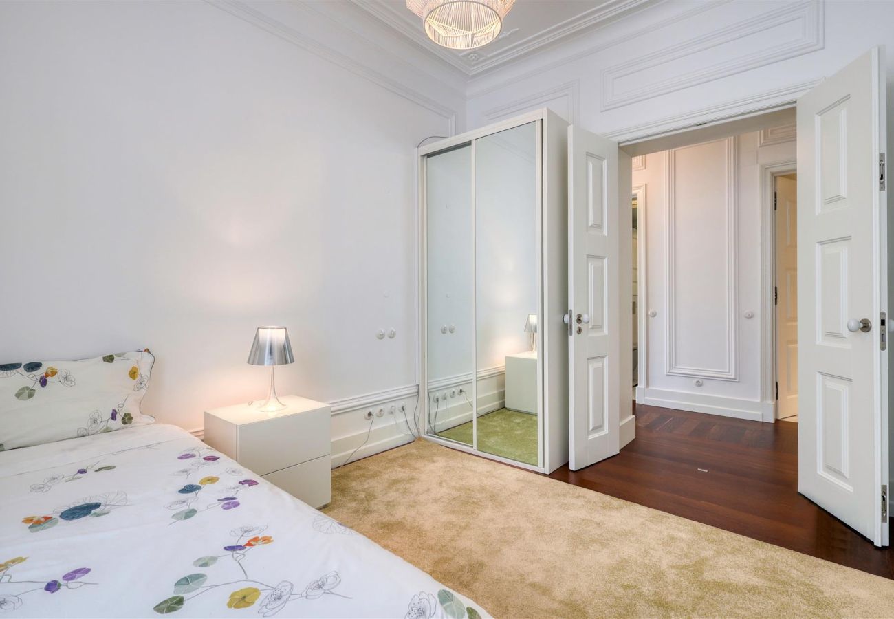 Comfortable bedroom with a single bed, mirrored wardrobe, and soft lighting, highlighting classic decor details.