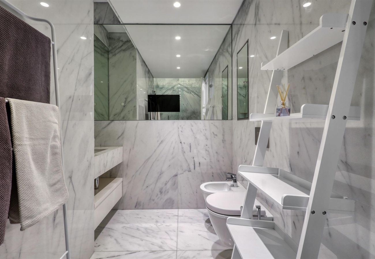 Sophisticated bathroom with white marble finish, modern shelves, and elegant towels.