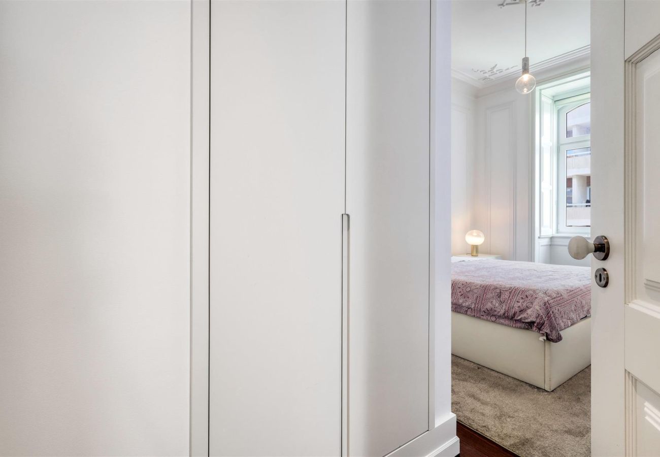 Small bathroom with elegant design, featuring white marble walls, a large mirror, and a compact sink.