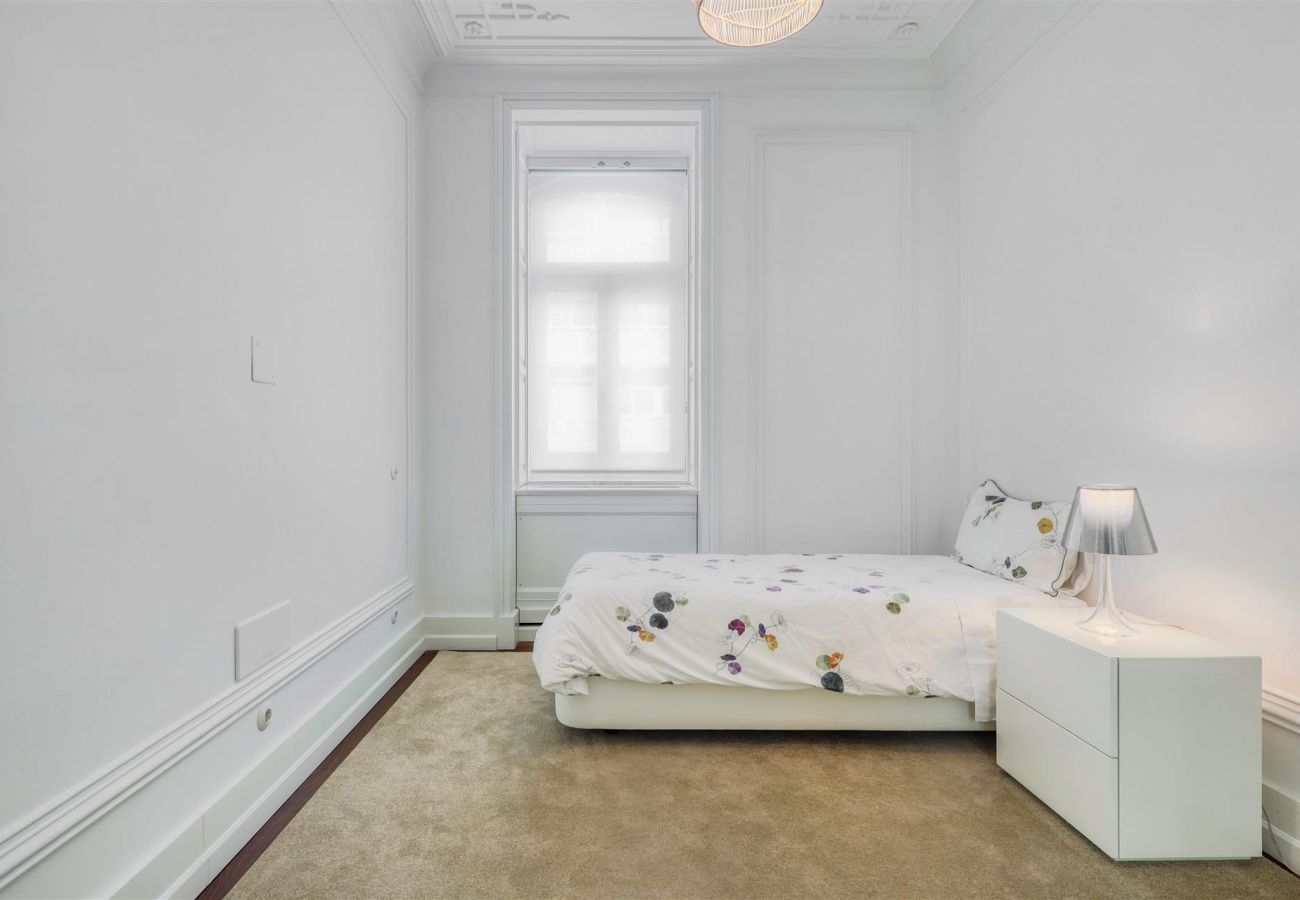 Spacious bedroom with a single bed and minimalist decor, enhanced by light tones and natural lighting.
