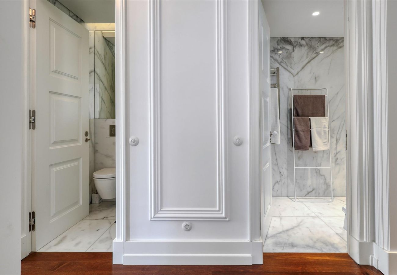 Elegant entrance to a marble-clad bathroom, featuring a classic design and refined details.