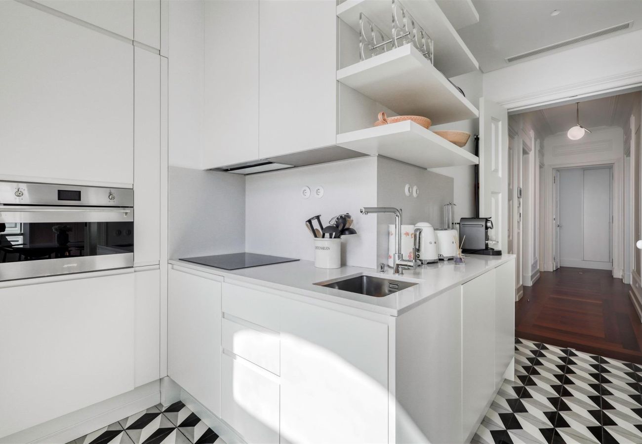 Sophisticated white kitchen with an integrated island, built-in oven, minimalist cabinets, and a black and white geometric floor.